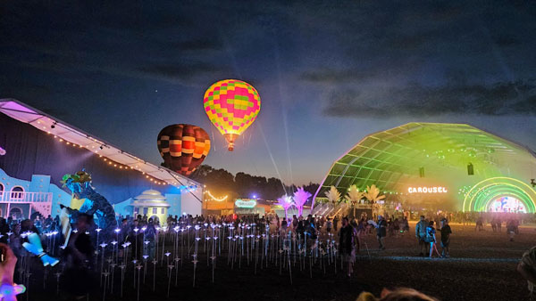 Hot air balloons rise above a stage.
