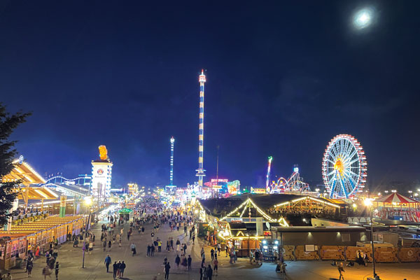 Lights from carnival games and rides light up the night sky.