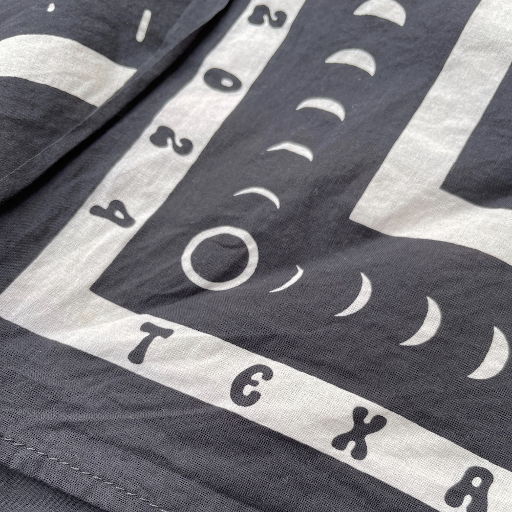 Black bandana with white lettering reading "Texas Eclipse 2024" and simple symbols of the sun and moon.