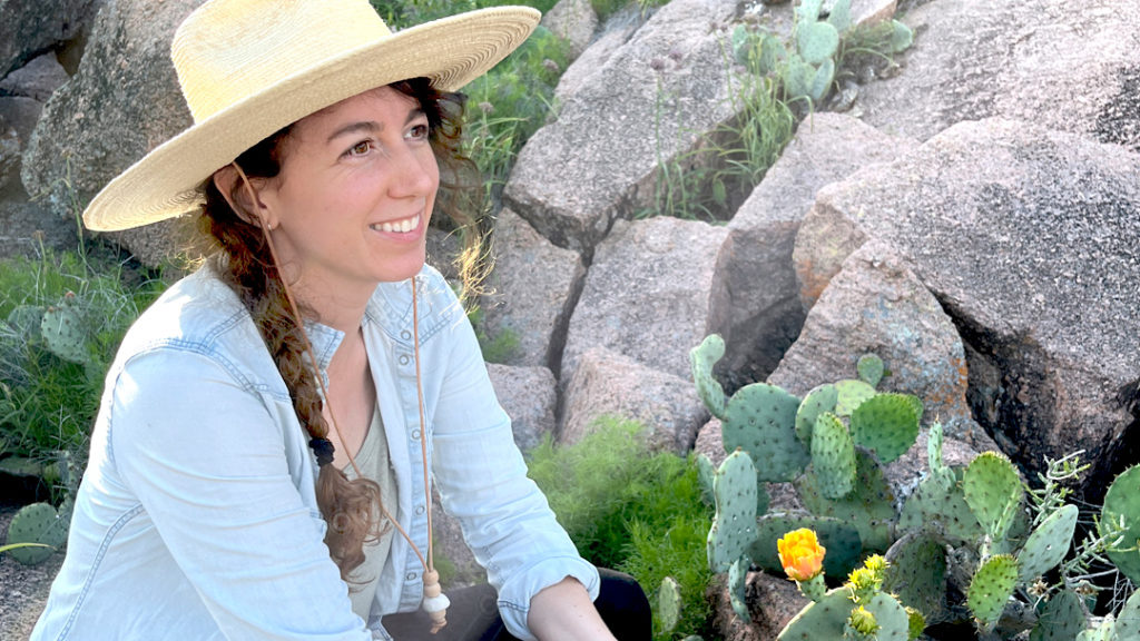 Cara sitting near a blooming cactus.