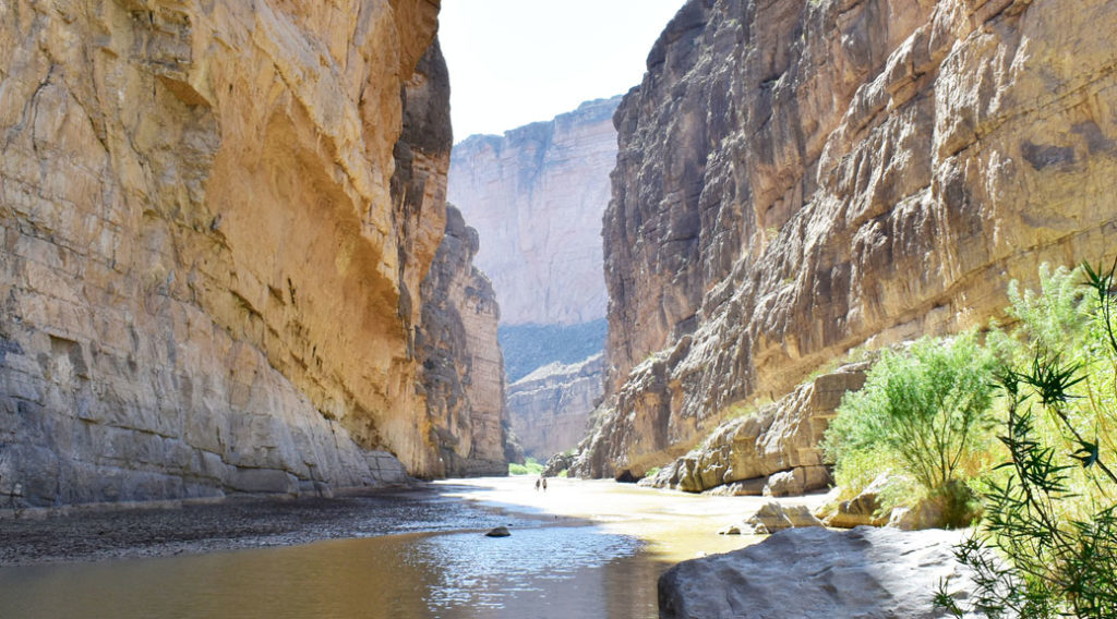 Steep canyon walls with the Rio Grande River flowing gently between them.