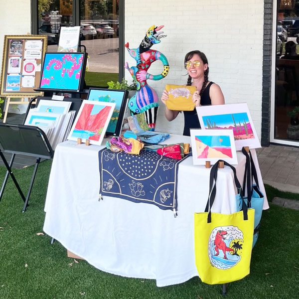 Cara sitting at table covered in colorful art prints.